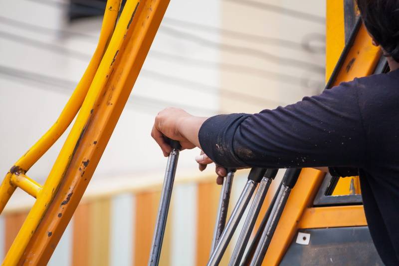 construction worker controls of lifting crane in crane truck